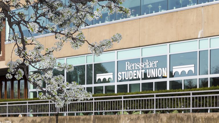 A view of the Rensselaer Student Union with blossoming trees.